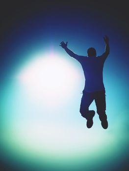 Man fly in air. Blue  Toned effect. Man falling down with raised arms. Sun and colorful sky background. Toned effect