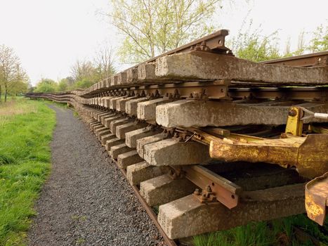 Wagon with extracted old railways. Concrete and wooden sleepers with rail rods in railway station stock waiting for transport to steel foundry for recycling.