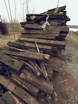 Terrible smell pile of extracted old wooden ties. Old oiled used oak railway sleepers stored after big reconstruction of old railway station. 