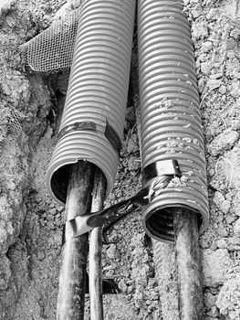 Excavation of trench  with black cables in protective HDPE tube. Lines of metallic and fiber optic cables, building of communication optical network. The installation of connection. 