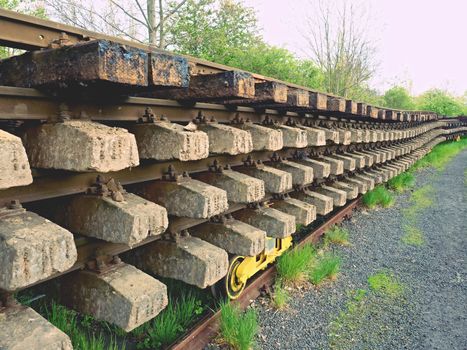 Wagon with extracted old railways. Concrete and wooden sleepers with rail rods in railway station stock waiting for transport to steel foundry for recycling.