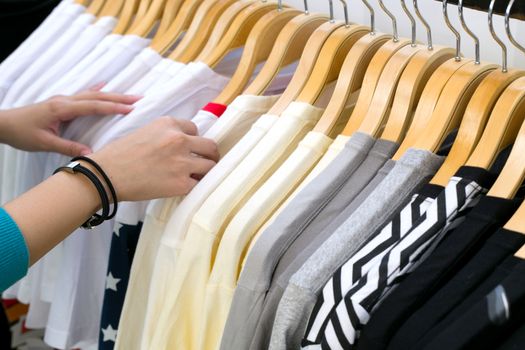 Young woman looking new shirt shopping in store.