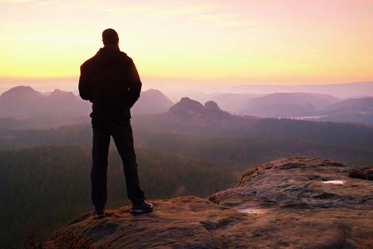 Tourist on the cliff of rock in rock empires park is watching over the misty and foggy morning valley to Sun