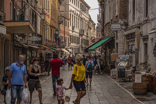 VENICE, ITALY 2 JULY 2020: Tourists walk in Venice street Gondolier in venice canal