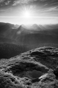 Sunrise in a beautiful mountain of Czech-Saxony Switzerland. Sandstone peaks increased from foggy background, the fog is orange due to sun rays. 