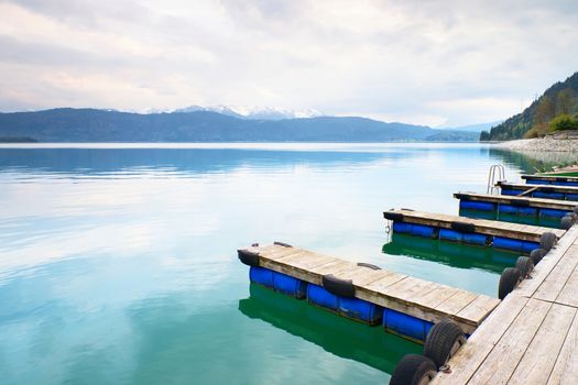 Blue Alps lake with Rental rowing boats in marina. Wharf for trip ships.