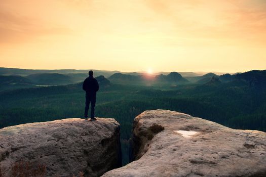 Hiker on the peak of sandstone rock in rock empires park and watching over the misty and foggy morning valley to horizon.