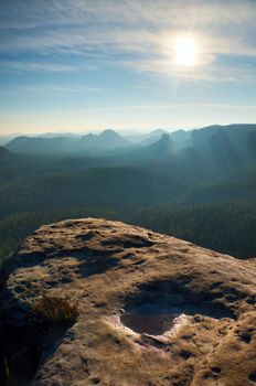 Spring misty morning in  forest landscape. Majestic peaks cut lighting mist. Deep valley is full of colorful fog and rocky hills are sticking up to Sun.