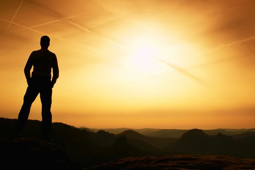 Tourist on the cliff of rock in rocky mountains park is watching over the misty and foggy morning valley to Sun