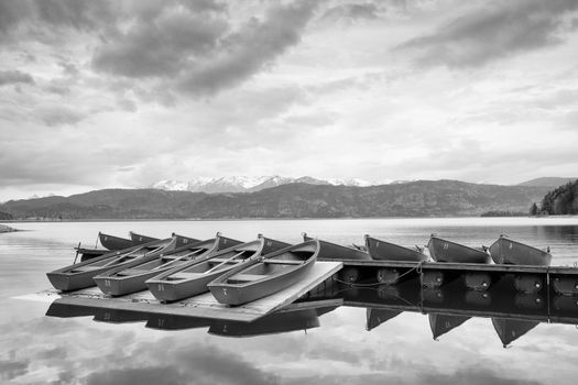Blue Alps lake with Rental rowing boats in marina. Wharf for trip ships.