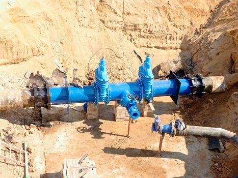 Big industrial gate valves in pipelines with big hand wheel. Repaired drink water pipeline in digged hole. The 500 mm diameter pipel.