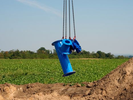New pipeline part hanging on crane hook. Transport of gate valve within conctruction period by crane.