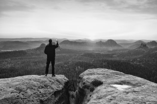 Man photography on peak of rock empire. Dreamy spring  landscape, orange pink mist