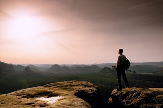 Tall hiker in mountains. Thinking man silhouette in nature within daybreak. The vignetting effect.