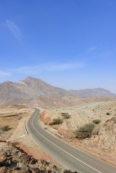 A road going thru the deserted mountains of the Sultanate of Oman