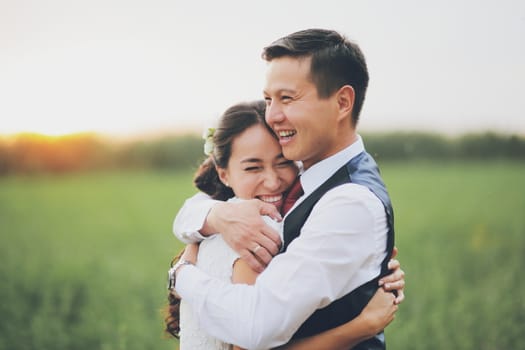 Happy bride and groom hug each other in the park at sunset. Wedding. Happy love concept. High quality photo