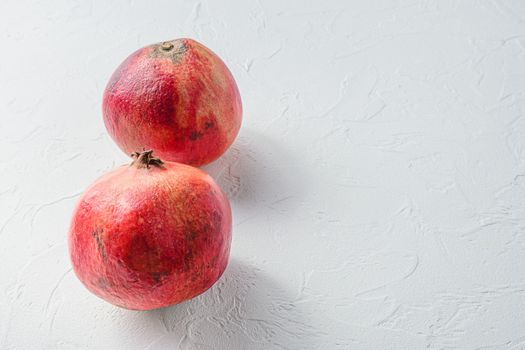 Fresh pair of pomegranate over white concrete background, side view space for text
