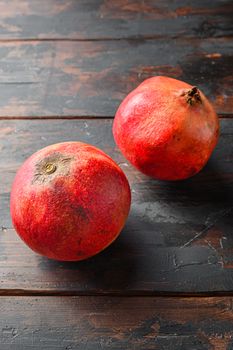 Ripe pomegranates over dark old wooden table, side view close up