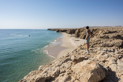 Woman admiring wild beach, coast of Ras Al Jinz, Sultanate of Oman