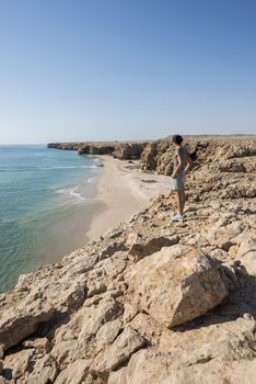 Woman admiring wild beach, coast of Ras Al Jinz, Sultanate of Oman