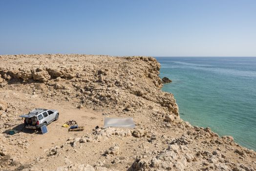 4x4 vehicle with solar panel in the wild coast of Ras Al Jinz, Sultanate of Oman. people camping in the nature with view on the ocean.