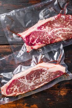 Vacuum packed fresh beef top blade steak for sous vide cooking on dark old wooden background, top view