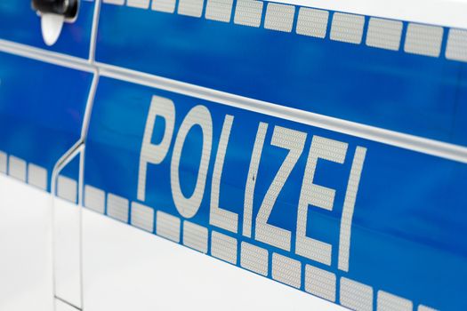 Inscription "Police" in white luminous colour on a blue background on the side of a police car, Germany