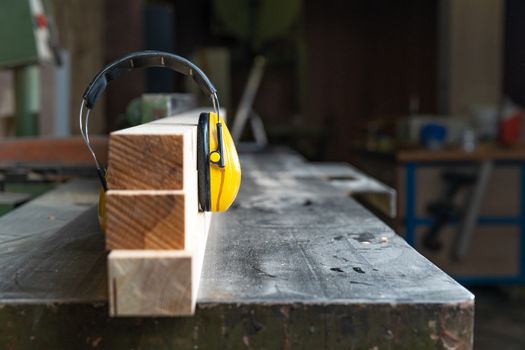 protective yellow headphone on wooden prism in joinery.