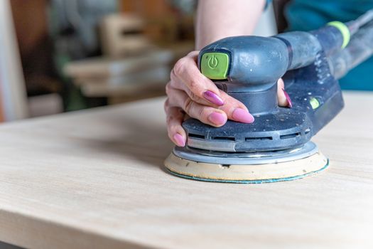 sanding wooden furniture using an electric hand grinder.