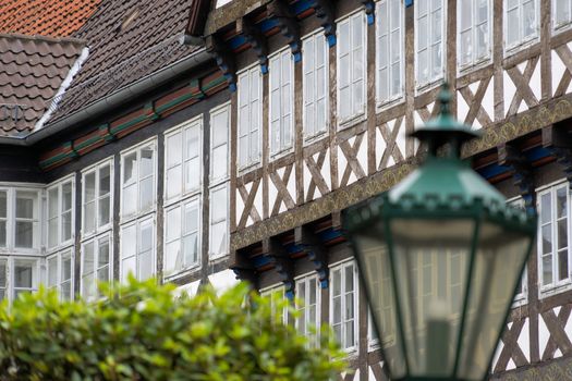 Facade of a half-timbered house in an old town, with a deliberately blurred lantern and a blurred crown of trees in the foreground, Germany