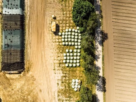 Aerial view of a farm warehouse, vertical photographed round silage bales wrapped in foils, made with drone