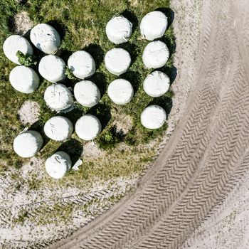 Round bales with silage as animal feed, wrapped in foil, vertical aerial view from above, made with drone