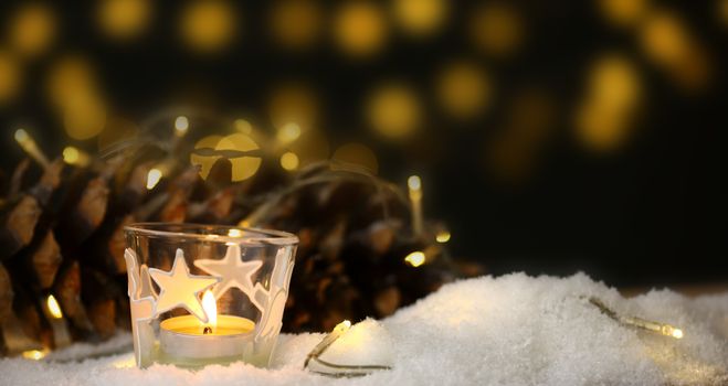 christmas theme with candles, snow, pine cone and christmas light with pokeh effect