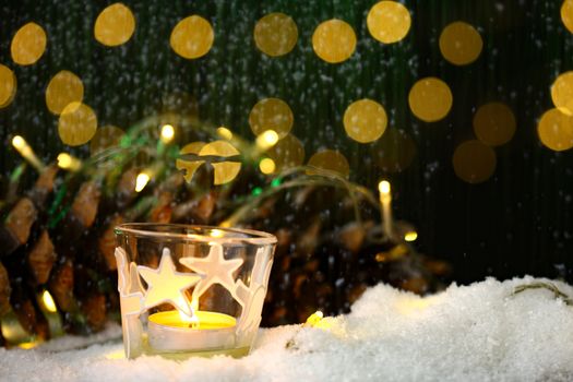 christmas theme with candles, snow, pine cone and christmas light with pokeh effect