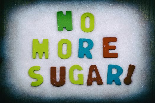 "NO MORE SUGAR!" Colorful text and letters in wood on white sugar crystals background and black border