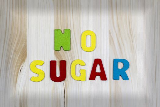 "NO SUGAR!" wriiten with colorful text wooden letters on wooden table with black border