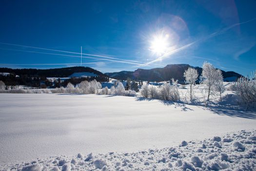 cold winter day in swiss mountains with sun reflections