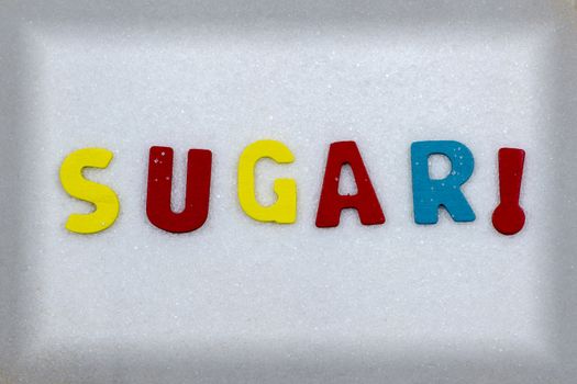 "SUGAR!" Colorful text and letters in wood on white sugar crystals background and light black frame