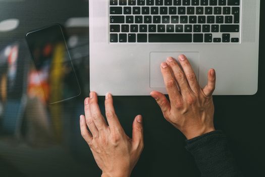 cyber security internet and networking concept.Businessman hand working mobile phone on laptop computer background