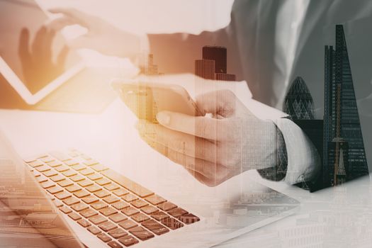 Hands of businessman using mobile phone in modern office with laptop and digital tablet computer ,with city exposure