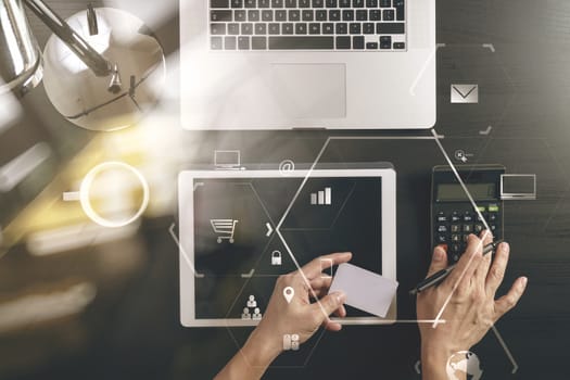 Internet shopping concept.Top view of hands working with calculator and laptop and credit card and tablet computer on dark wooden table background with Vr diagram