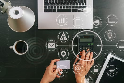 Internet shopping concept.Top view of hands working with calculator and laptop and credit card and tablet computer on dark wooden table background with Vr diagram