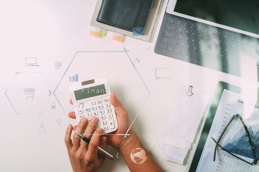 top view of businessman hand working with finances about cost and calculator and latop with mobile phone on withe desk in modern office with VR icon diagram