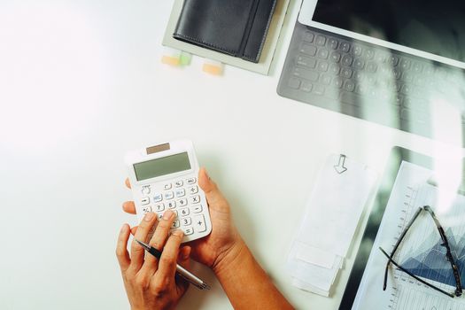 top view of businessman hand working with finances about cost and calculator and latop with mobile phone on withe desk in modern office 