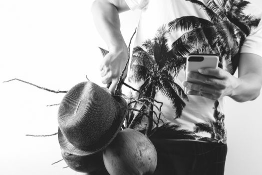 Summer and holiday fashion concept.Man Wearing palm trees graphics on T-shirt and holding cluster of coconuts with mobile phone,black and white