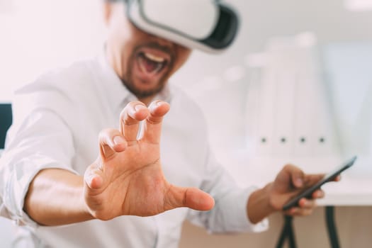 businessman wearing virtual reality goggles in modern office with mobile phone using with VR headset 