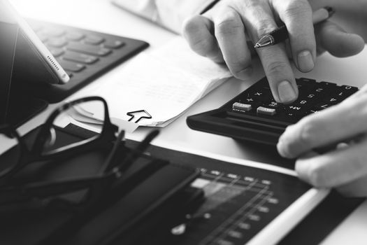 close up of businessman hand working with finances about cost and calculator and latop with mobile phone on withe desk in modern office,black and white