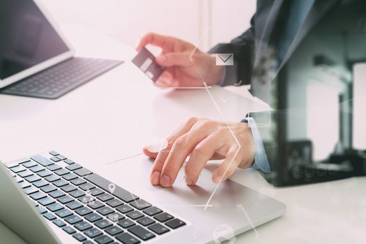 businessman making credit card purchase online with laptop computer on modern desk with VR icon diagram