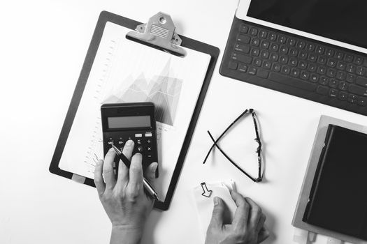 top view of businessman hand working with finances about cost and calculator and latop with mobile phone on withe desk in modern office ,black and white