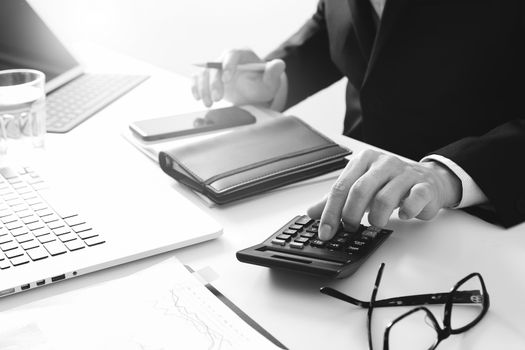 businessman hand working with finances about cost and calculator and latop with mobile phone on withe desk in modern office,black and white